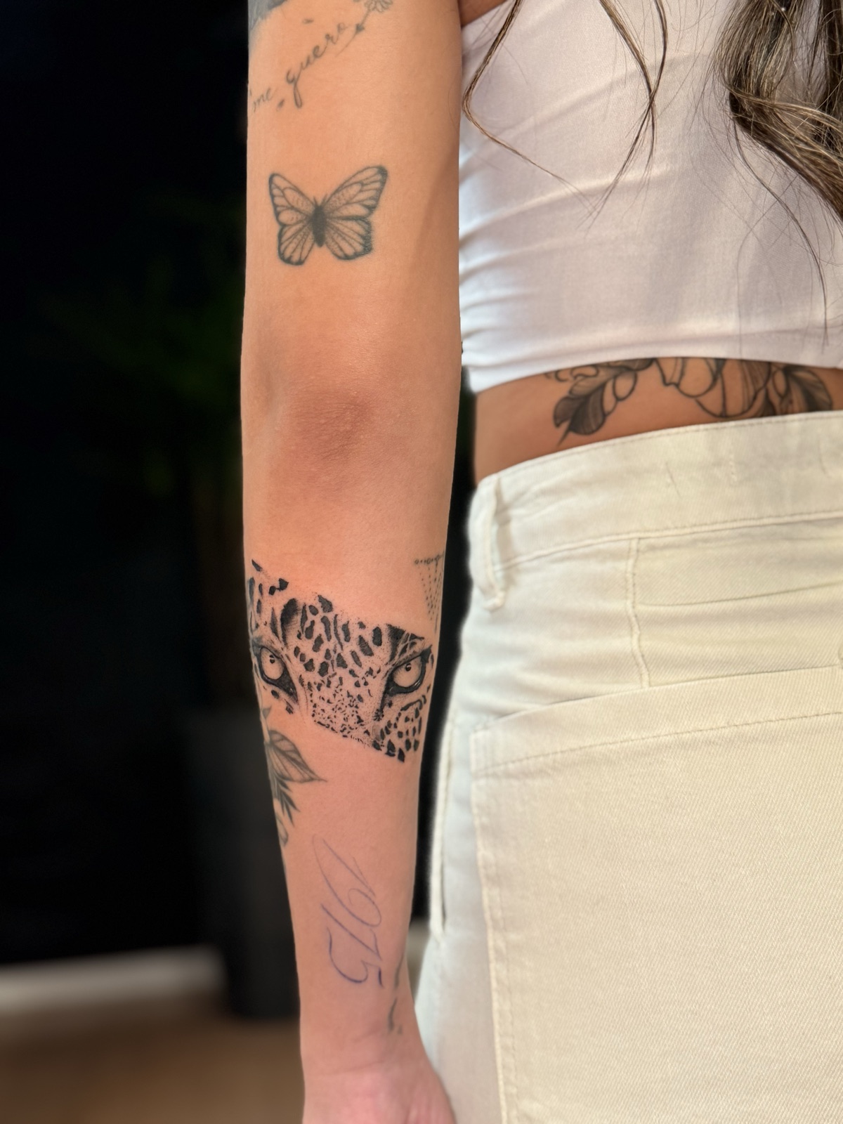 Olhos de onça em blackwork com pintas sólidas e sombra pontilhada, em faixa no antebraço. Por Dudis (Maria Eduarda Freitas), na ADV Tattoo.